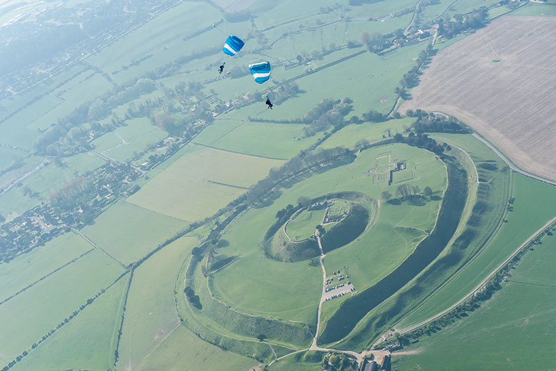 Parachutes in distance over green fields