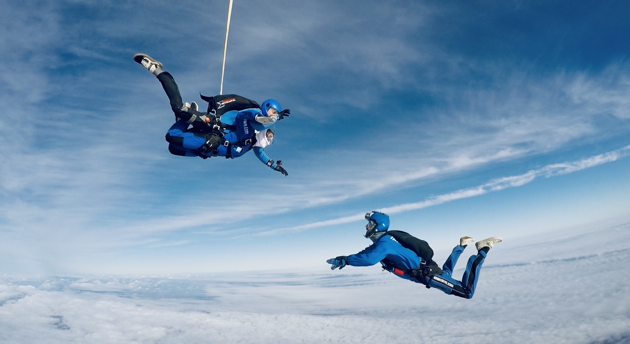Camera operator and tandem skydiver in freefall facing each other